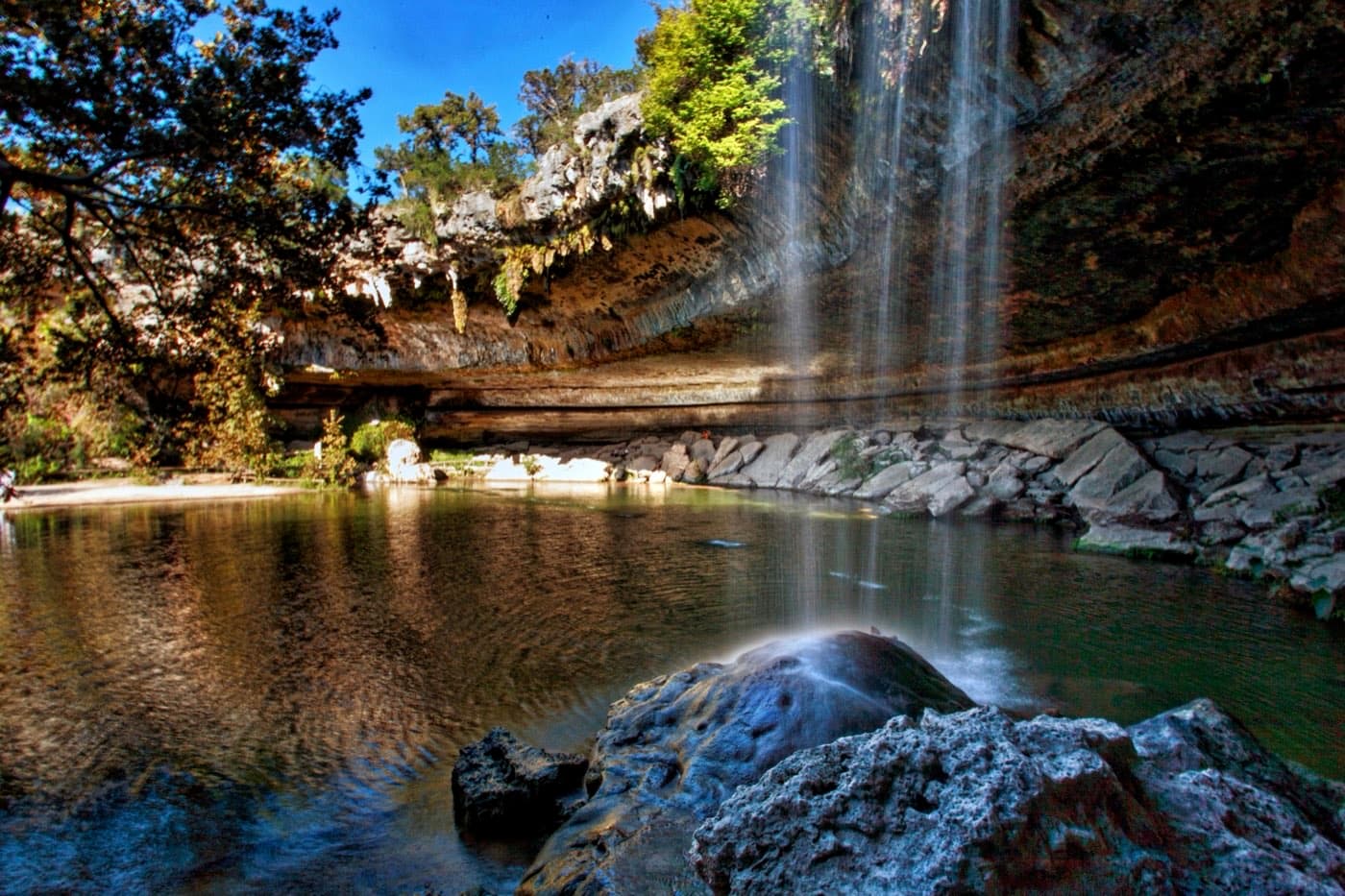 The waterfall spilling over the collapsed grotto rim into the green water of Hamilton Pool Preserve