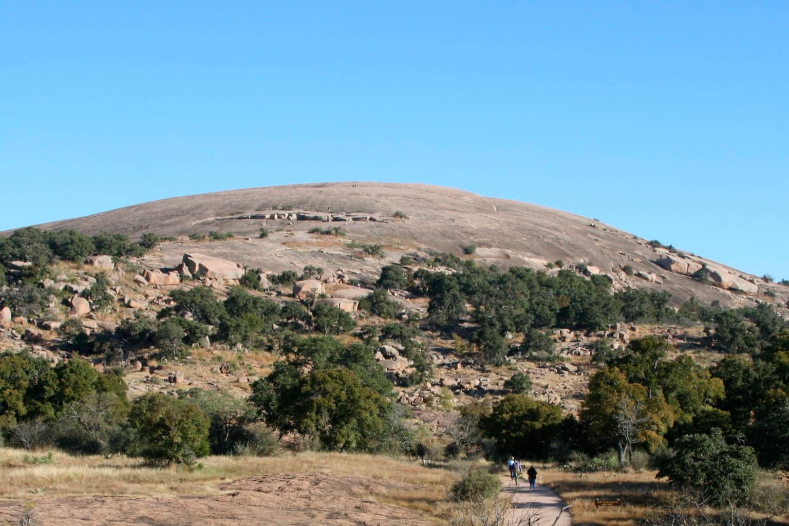 The pink granite dome of Enchanted Rock rising over Hill Country brush north of Fredericksburg