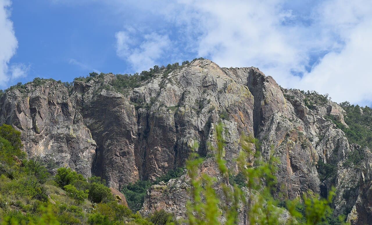 The rock face of Toll Mountain rising over green desert scrub in the Chisos Basin of Big Bend National Park