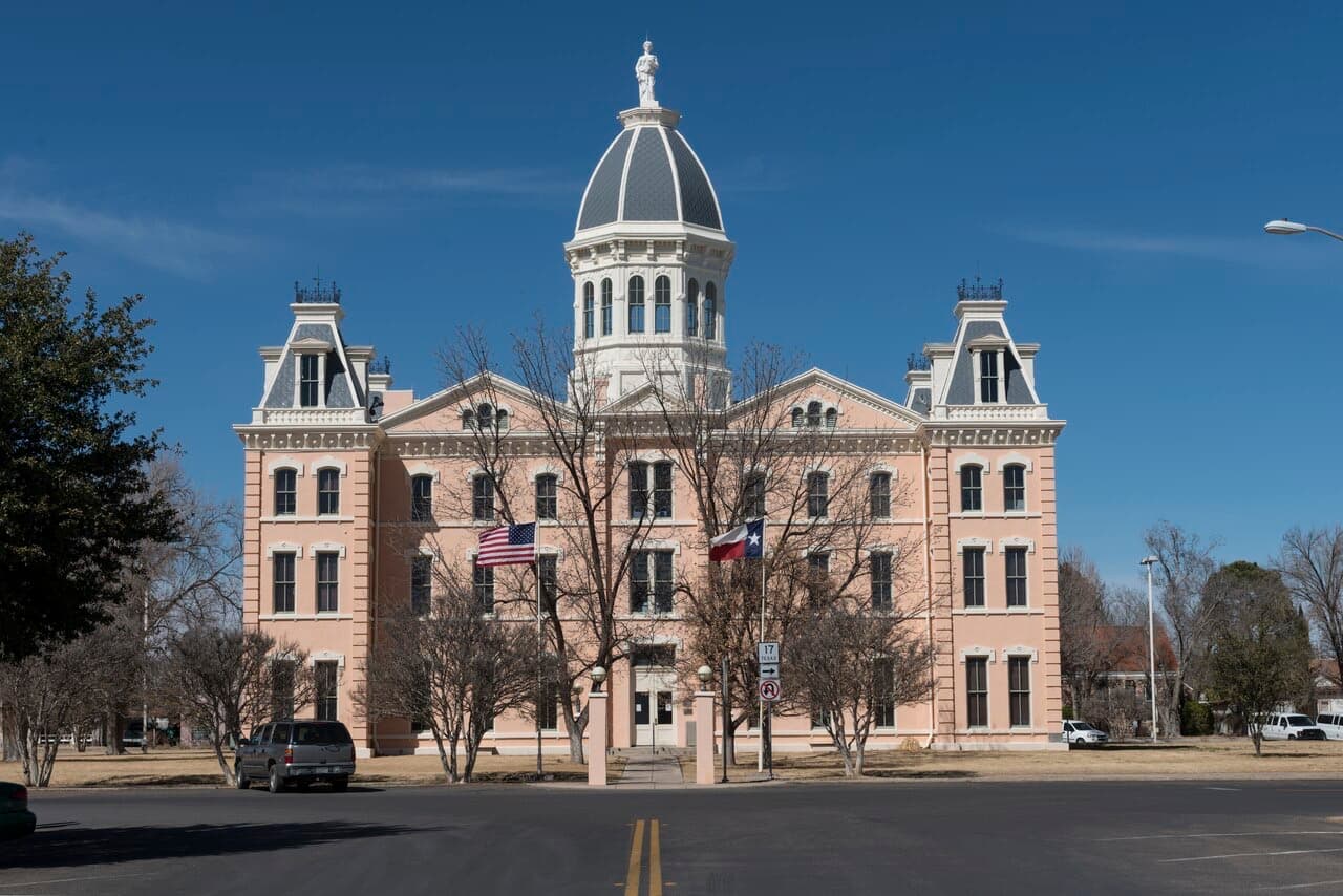 The pink Second Empire facade and domed cupola of the Presidio County Courthouse in Marfa under a deep blue sky