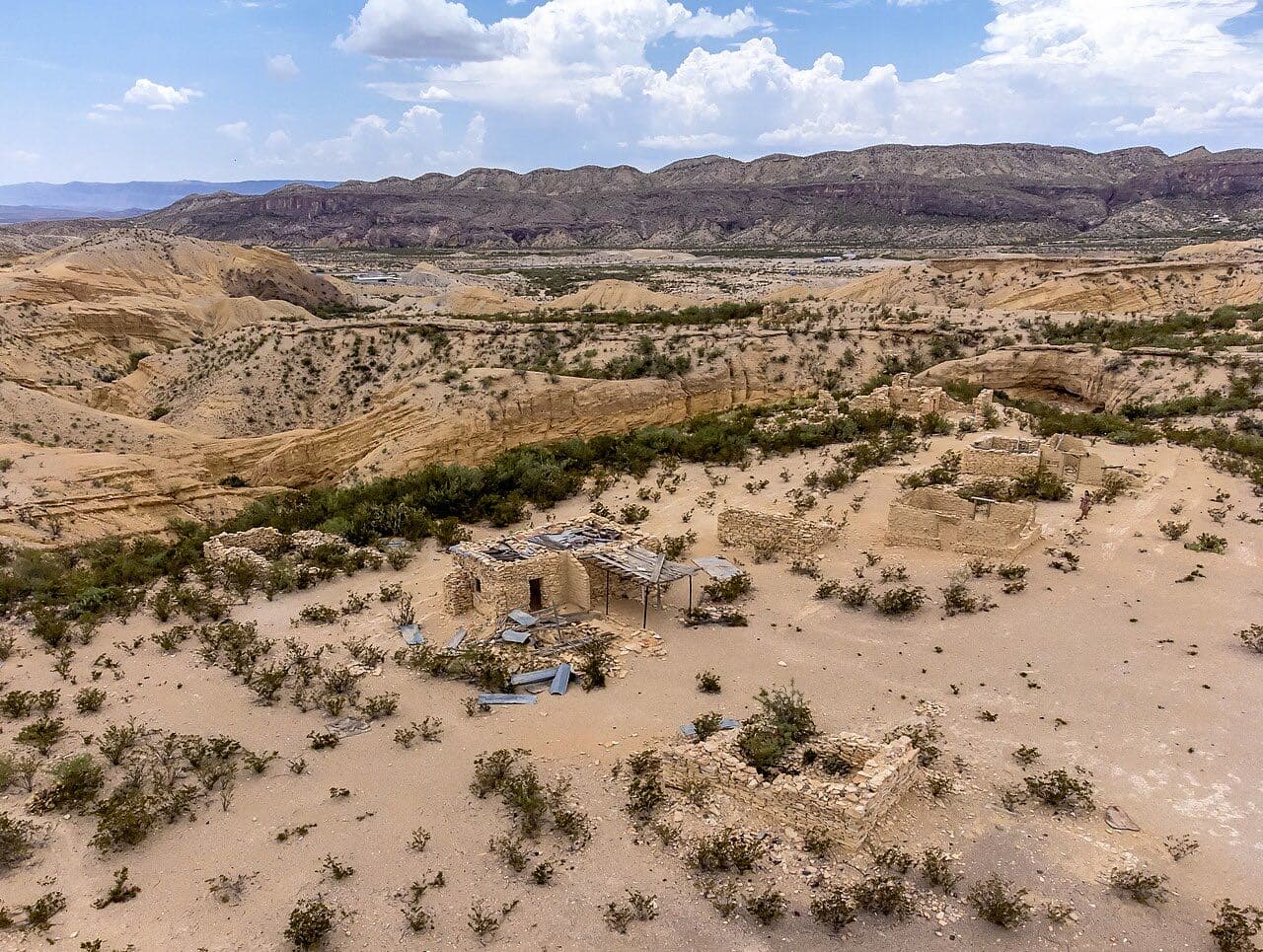 Stacked-stone ruins of miners' homes scattered across the desert hills of Terlingua ghost town under West Texas clouds