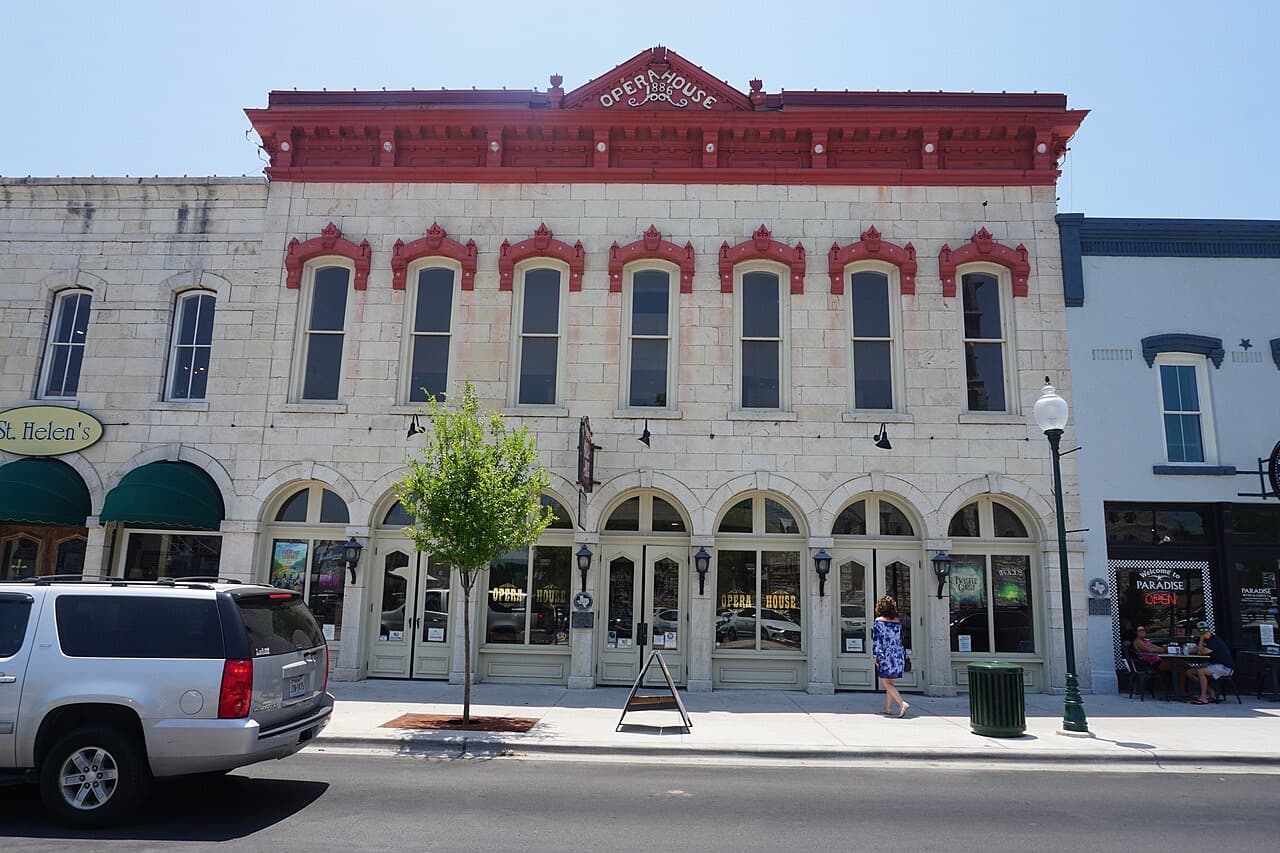 The 1886 Granbury Opera House's limestone and red-trimmed facade on the courthouse square, with sidewalk cafe tables next door