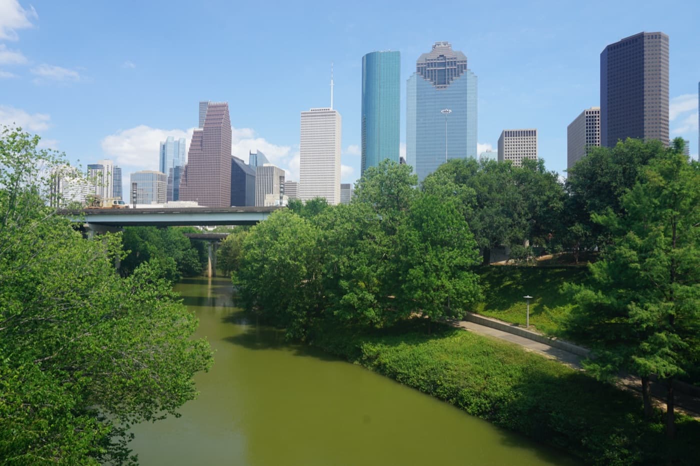 Buffalo Bayou Park's green trails with the downtown Houston skyline rising behind them