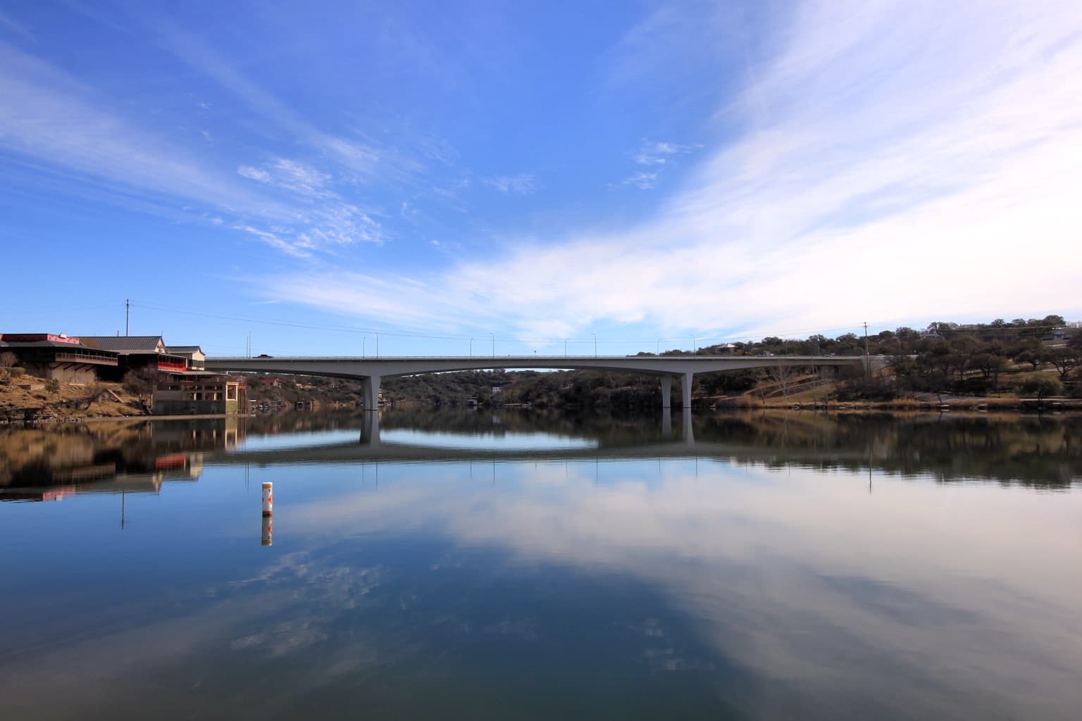 Lake Marble Falls under granite bluffs, with the US 281 bridge crossing in the background