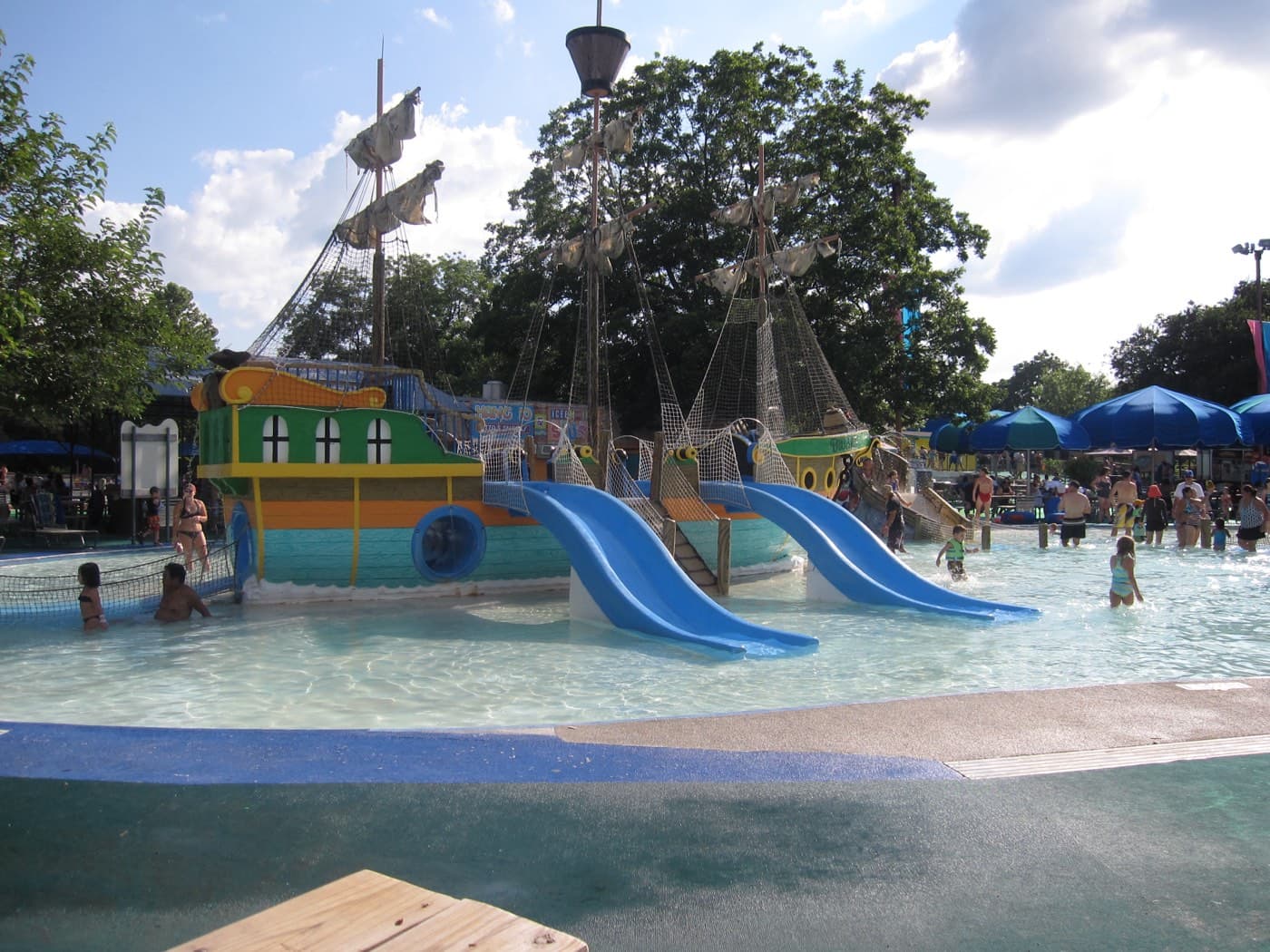 Families splashing around the pirate-ship kiddie pool and blue waterslides at Schlitterbahn waterpark in New Braunfels