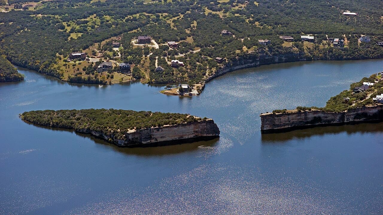 Aerial view of Hell's Gate at Possum Kingdom Lake, twin tree-topped limestone cliffs split by a channel of deep blue water