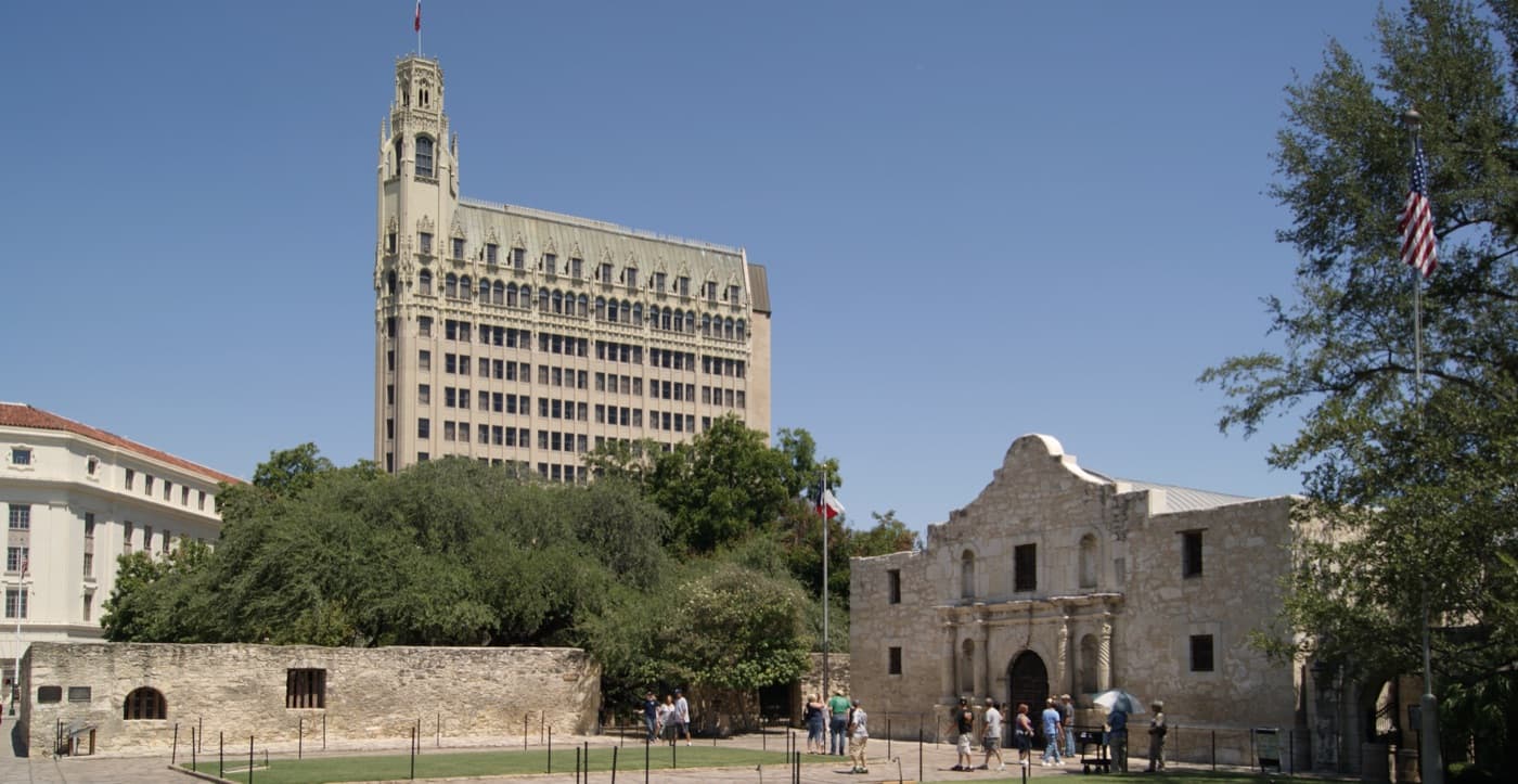 The stone facade of the Alamo church in downtown San Antonio under a bright sky