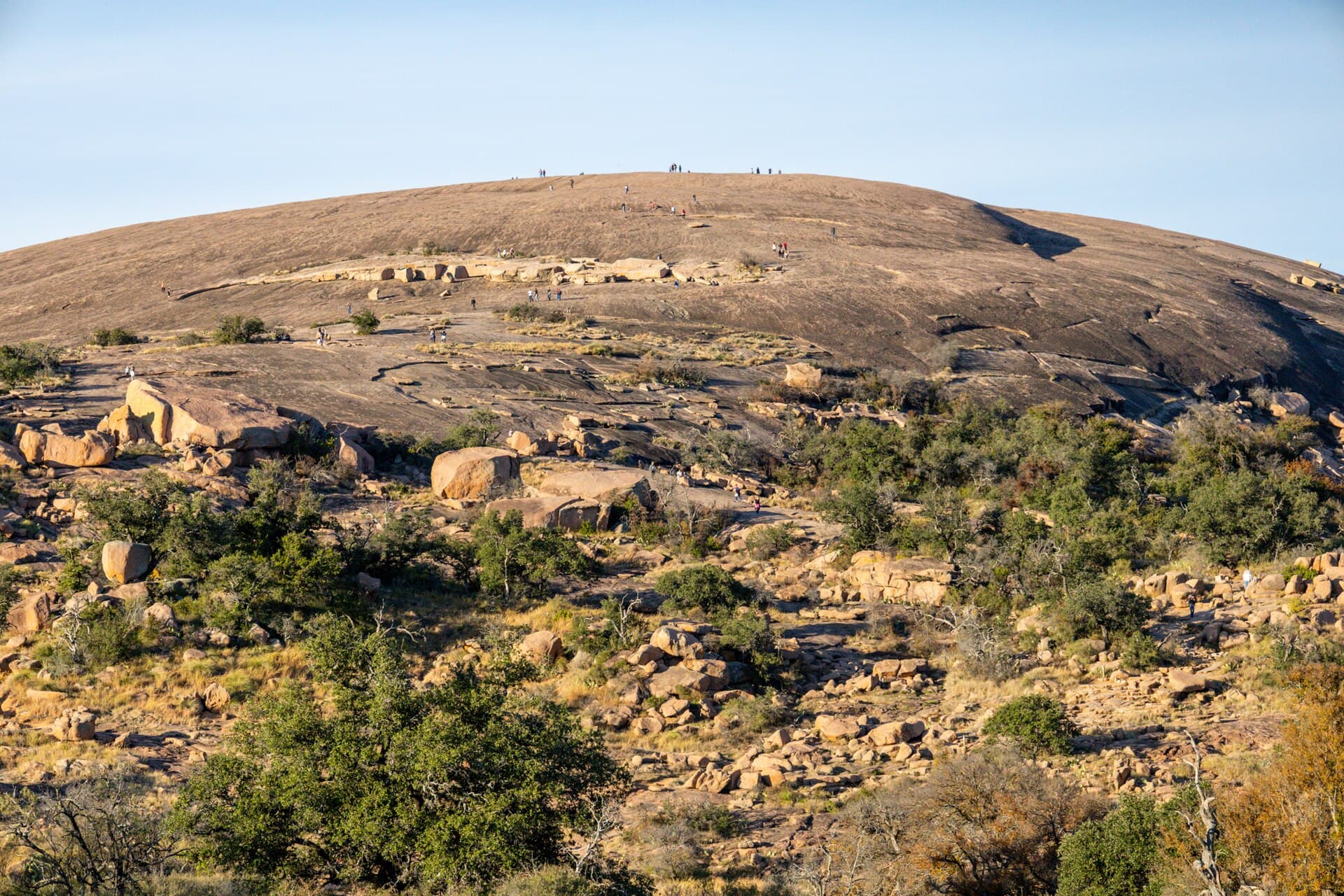 Hikers ascending the pink-granite dome of Enchanted Rock State Natural Area near Fredericksburg, Texas