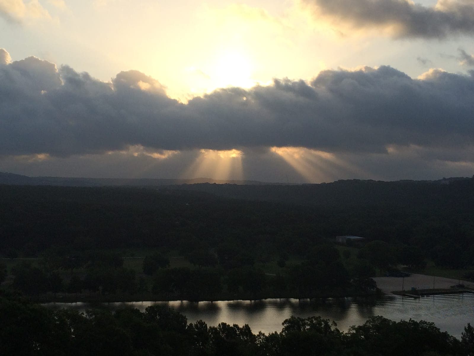Sunlight beaming through clouds onto the Texas Hill Country landscape near Austin