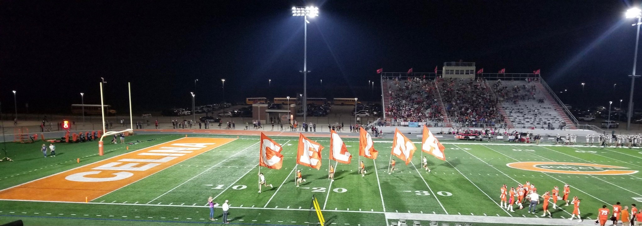 A Texas high school football field at night with stadium lights blazing, capturing the Friday Night Lights atmosphere filmed in the Austin area