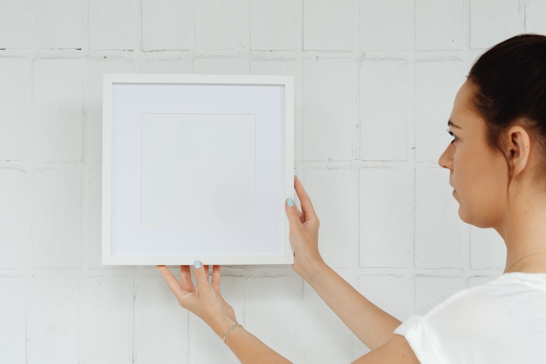 A person using a stud finder on a living room wall before starting a gallery wall project