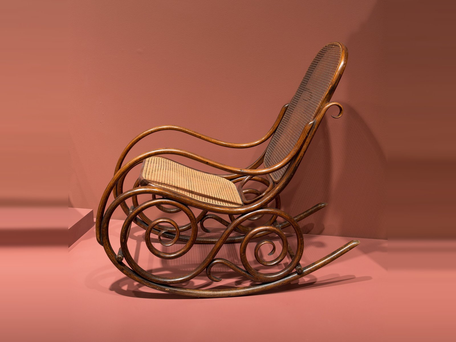A Viennese bentwood rocking chair with a cane seat and back and looping scroll runners