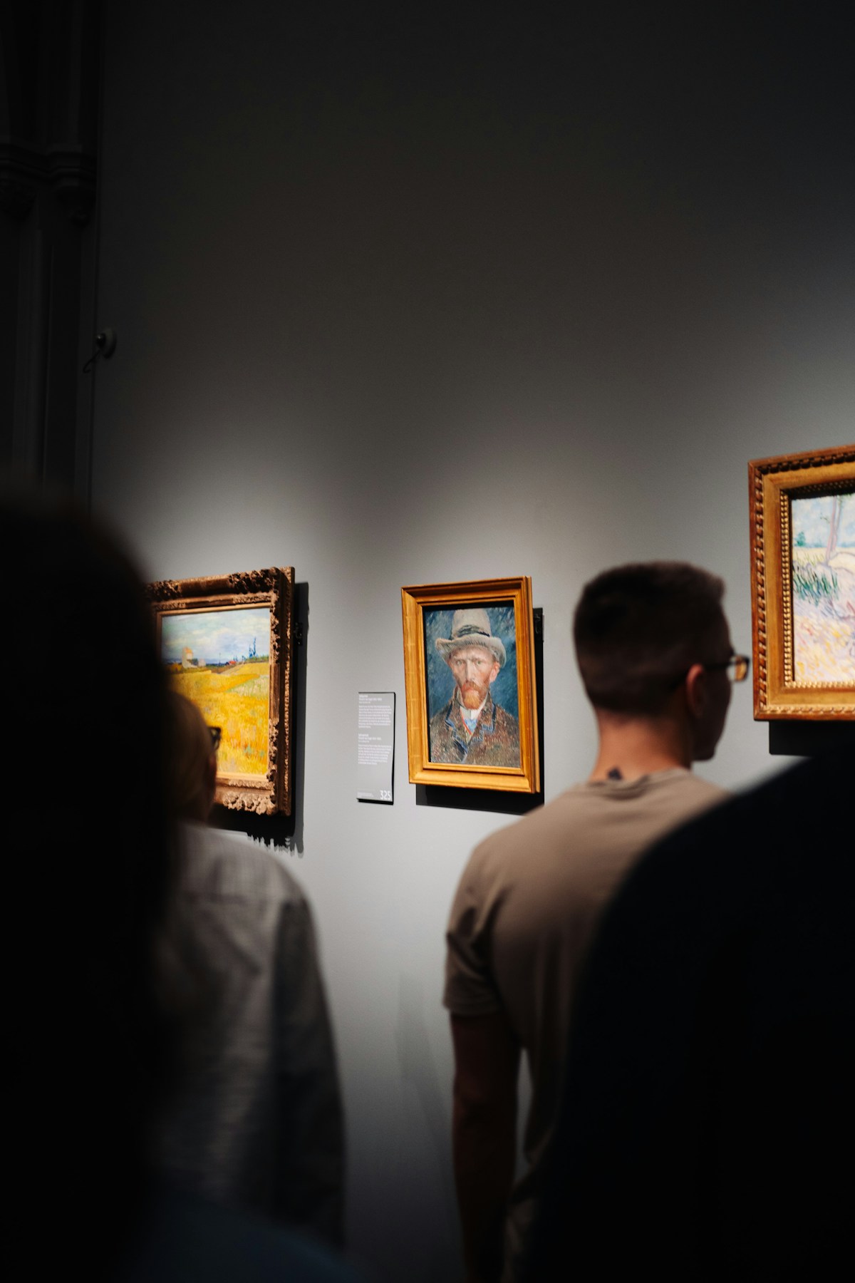 Visitors examining paintings at a museum gallery — the same careful attention you should bring to evaluating inherited artwork