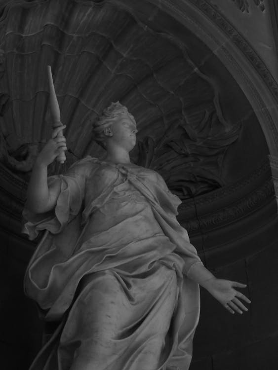 A sculpture on a pedestal illuminated by directional lighting creating dramatic shadows