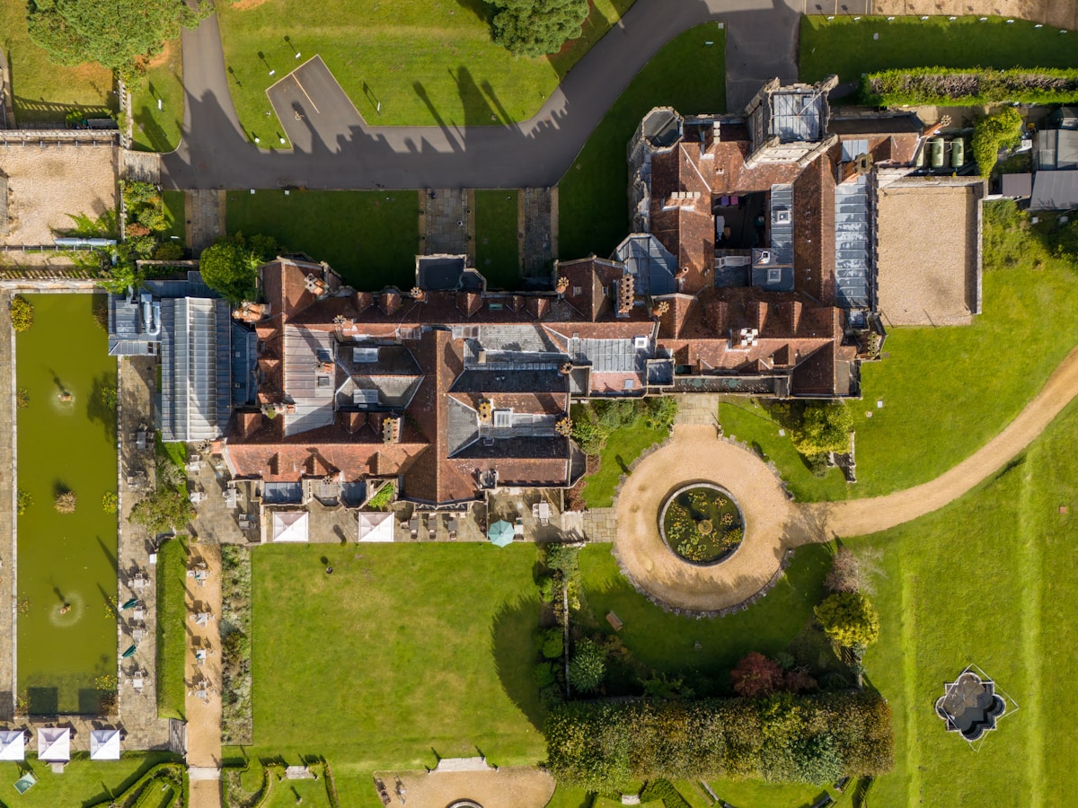Aerial view of a historic manor estate surrounded by manicured gardens