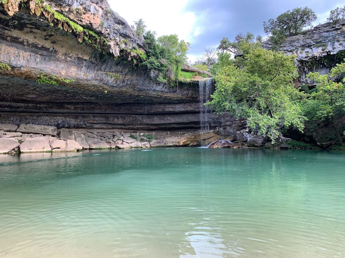 Hamilton Pool Preserve waterfall and grotto surrounded by green trees in Dripping Springs, Texas