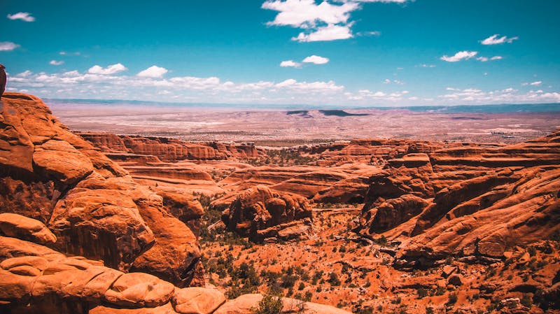Red rock desert landscape stretching to the horizon under blue sky -- the kind of Southwest vista that has inspired western artists for over 150 years