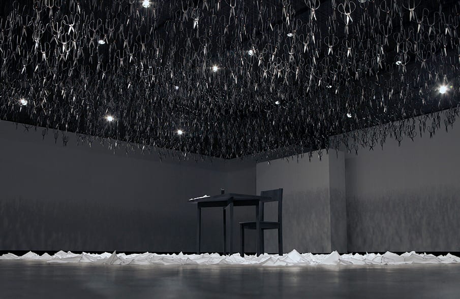 Beili Liu's installation The Mending Project — hundreds of scissors suspended point-down above a mending table