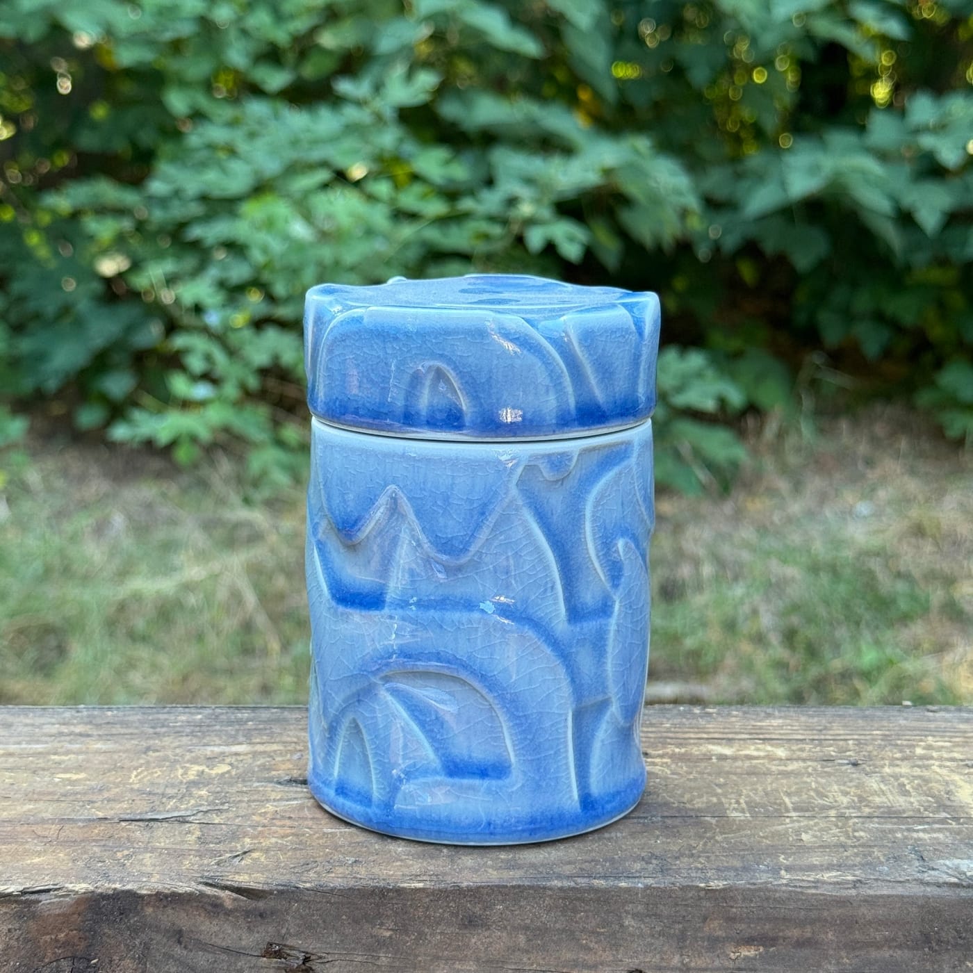 A lidded soda-fired porcelain jar by Ryan McKerley in a soft blue glaze with water-carved surface patterns