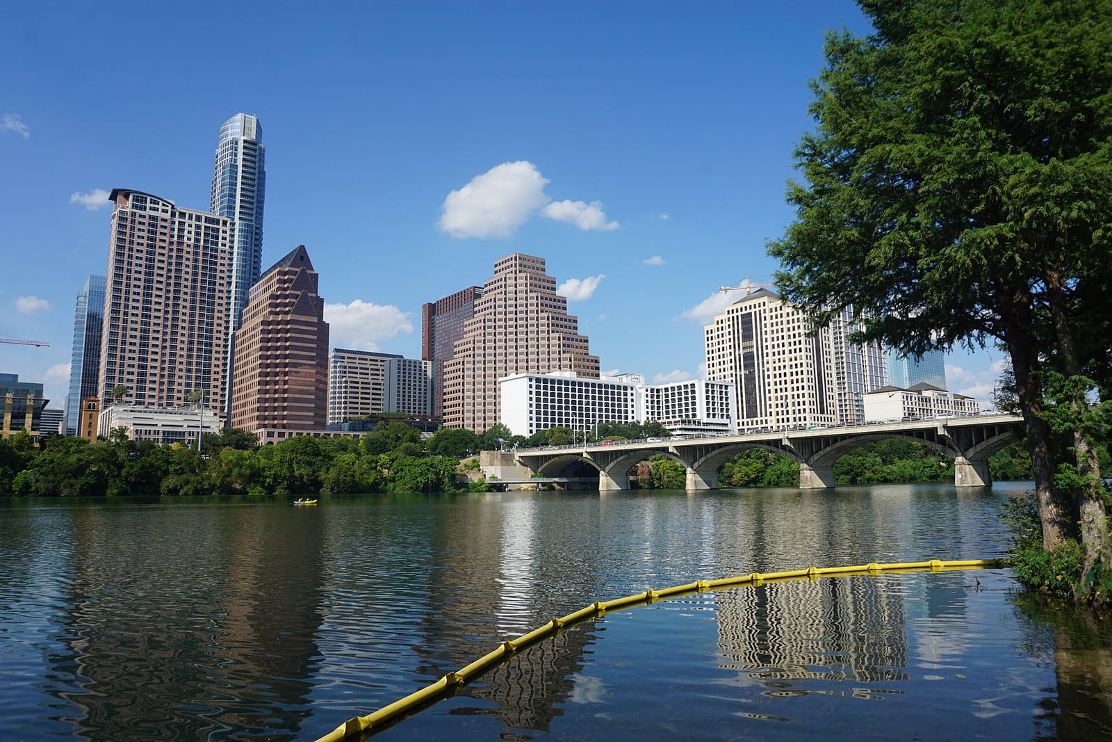 The downtown Austin skyline rising across the calm water of Lady Bird Lake at dusk