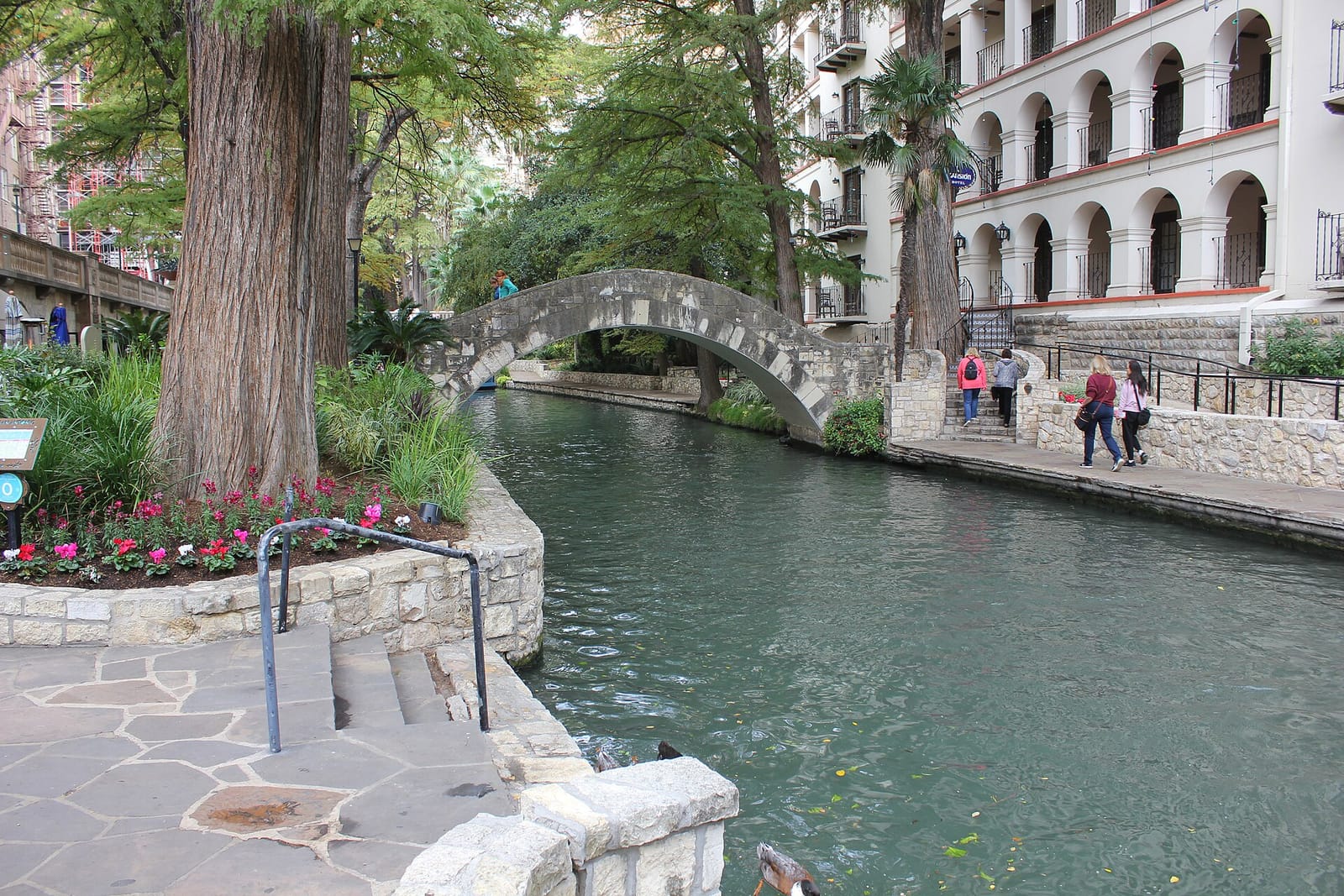 Arched stone footbridges crossing the river level of the San Antonio Riverwalk