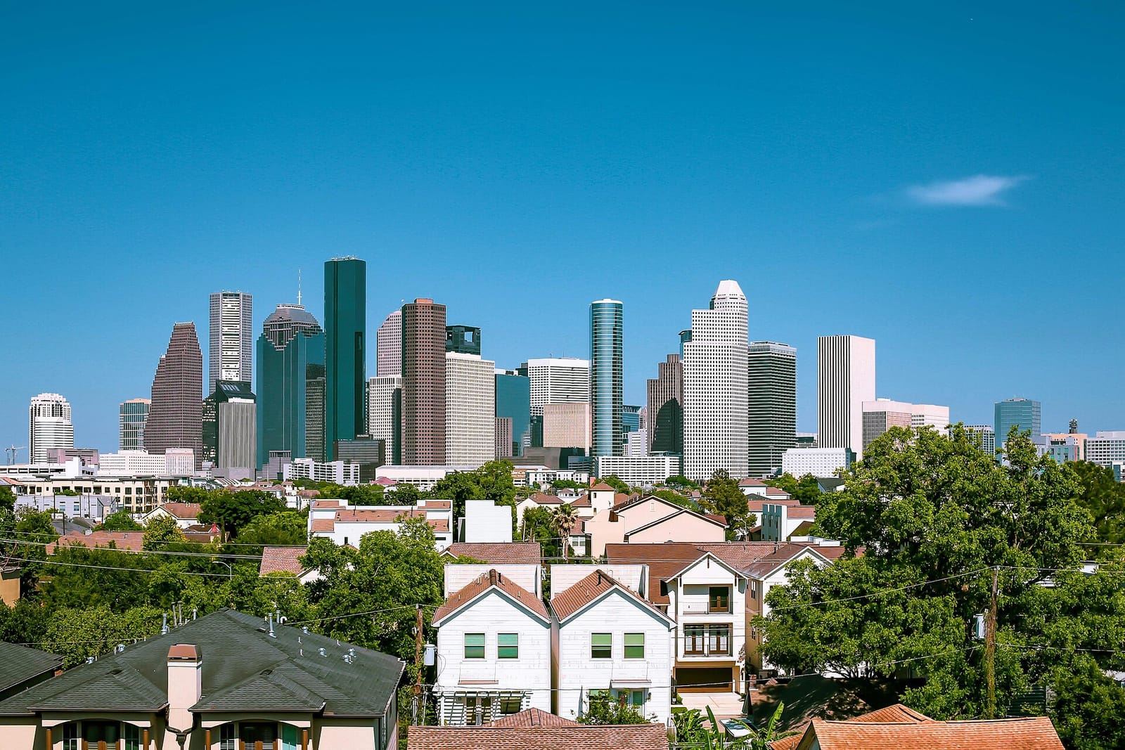 The Houston skyline rising beyond green bayou parkland at dusk