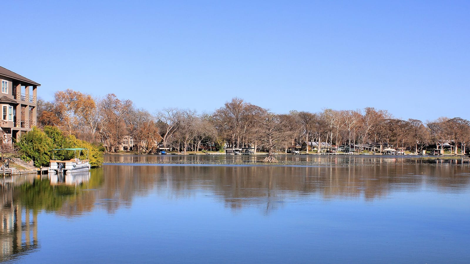 A calm morning on Lake McQueeney with a wooden dock and cypress trees at the water's edge