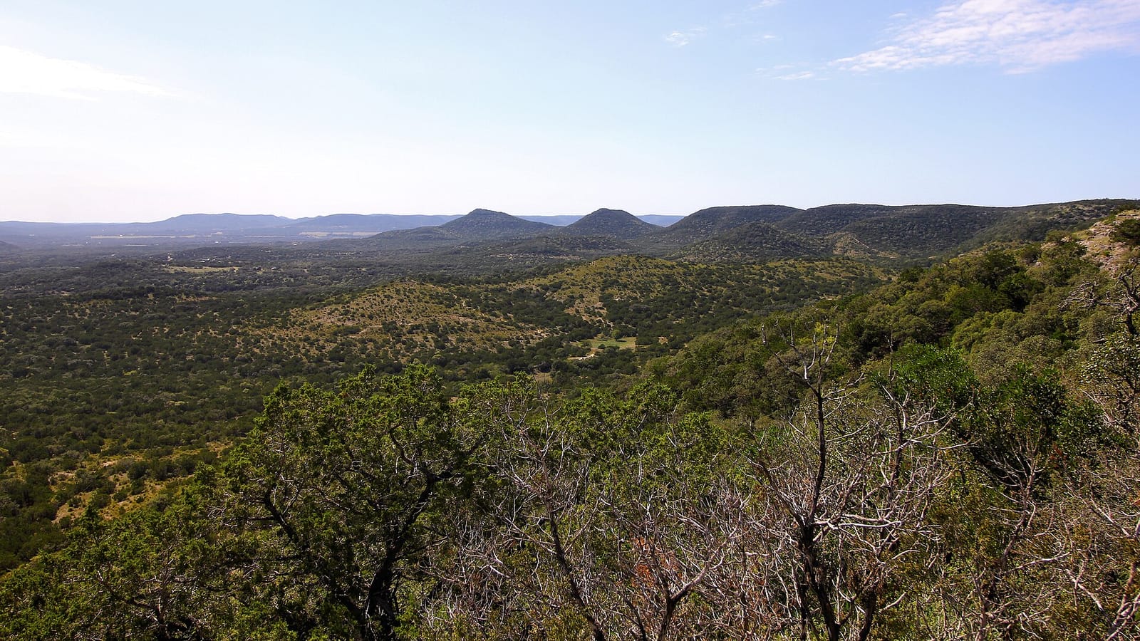 Cedar-covered Hill Country ridgelines rolling toward the horizon under a wide open sky